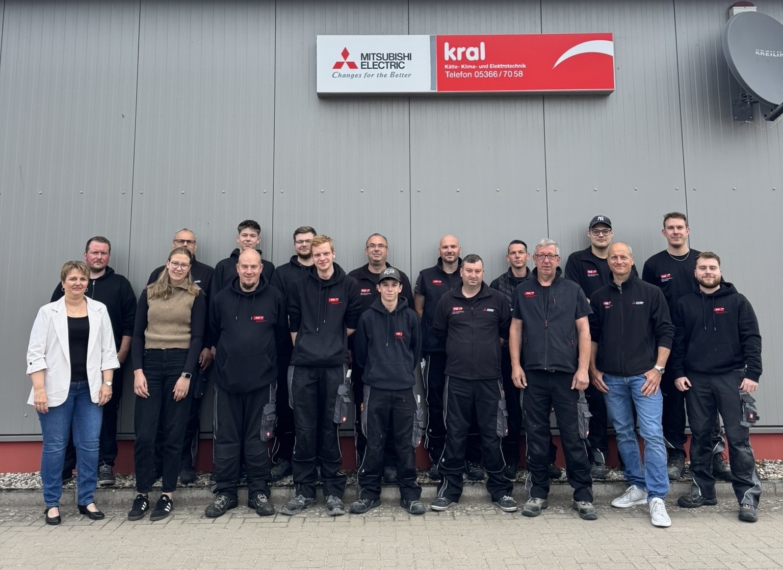 Eine Gruppe von Personen steht vor der Kral GmbH als Team zusammen